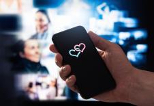 Ruka drži mobilni telefon sa dva srca na ekranu