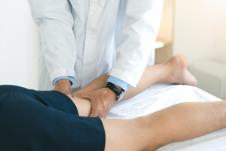 fizioterapeut pregleda blagim pritiskom sa oba palca prostor iza desnog kolena pacijenta koji leži na stomaku