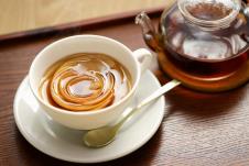 šolja čaja od jabuke u kojoj se nalazi kora od jabuke savijena u obliku ruže, čajnik na stolu