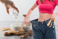 mlada žena koja na farmerkama pokazuje koliko je smršala/ovseno mleko