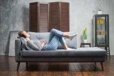 mlada žena leži na sofi i sluša muziku preko slušalica