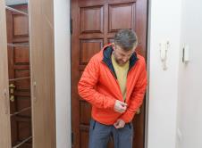 Muškarac u hodniku oblači narandžastu jaknu