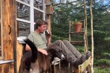 Andres Bojzen pije kafu na tremu drvene kuće u šumi.jpg