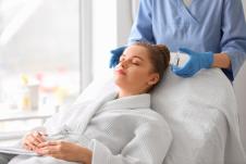 malda žena na tretmanu lepote kod dermatologa koji u rucu drži ampulu sa serumom