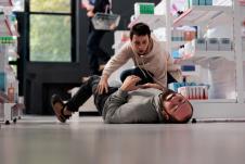 čovek koji ima napad epliepsije leži na podu, a pored njega je momak koji pokušava da mu pomogne