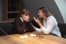 Žena plače za stolom, a druga je teši