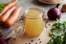 tegla supe od kostiju sa povrćem na stolu, šargarepa, pešun, crveni luk