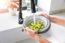 Krupni plan ženskih ruku iznad sudopere, žena pere belo grožđe