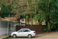 Beli auto parkiran ispred dvorišta kuće