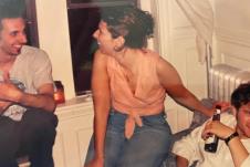 Žena sedi na naslonu stolice pored tadašnjeg dečka dok se u pozadini nalazi muškarac koji će kasnije postati njen suprug