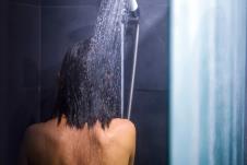 devojka okrenuta leđima se tušira u mraku