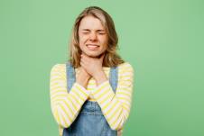 mlada žena se se guši od alergije i drži za vrat, osip po licu, zelena pozadina