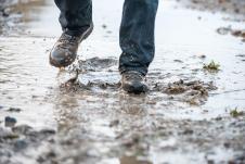 Osoba po kiši hoda kroz bare i blato