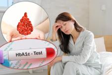 umorna žena sa anemijom sedi na ivici kreveta i drži se za glavu/kapljica krvi/HbA1c test