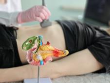 žena u crnoj majci leži na leđima na stolu u ordinaciji na ultrazvučnom pregledu pankreasa