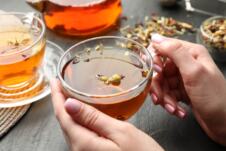 krupan plan ženskih ruku koje drže staklenu šolju sa biljnim čajem