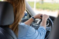 Žena u plavoj košulji vozi auto