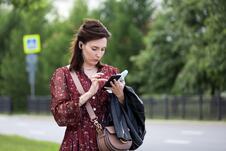 mlada žena na ulici gleda u telefon