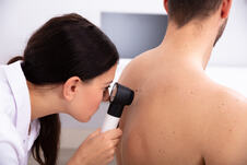 dermatolog pregleda leđa muškaraca dermoskopom