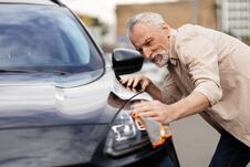 čovek čisti farove na automobilu