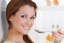 Nasmejana devojka drži kašiku kraj usana