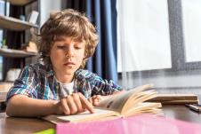 stockphotoconcentratedlittleboyreadingbookwhiledoinghomeworkalone701447971.jpg