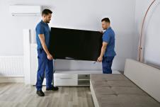 1204--stockphototwoyoungmalemoversinuniformplacingtelevisioninlivingroom757879099.jpg