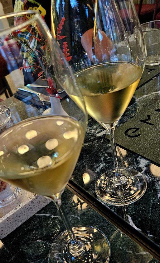Dve čaše belog vina na stolu od tamnog mermera u restoranu