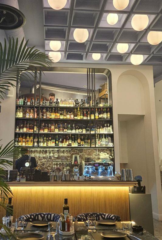 Moderan bar sa policama punim alkoholnih pića i osvetljenim šankom u restoranu