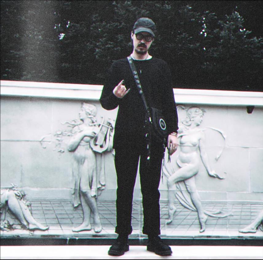 Šon Najt Nikolson skroz u crnom pozira ispred zida.jpg