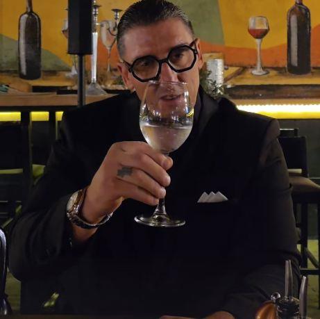 Kristijan Golubović u crnom odelu pije kiselu vodu