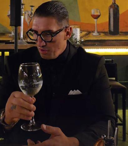 Kristijan Golubović u crnom odelu pije kiselu vodu