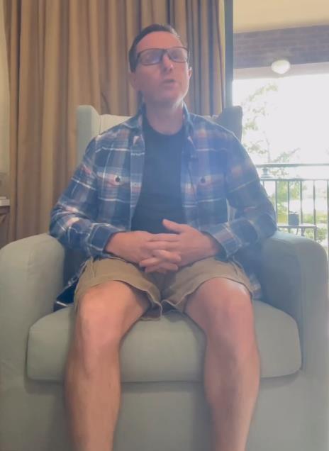 Džastin Dorf u kariranoj košulji sedi na fotelji.jpg