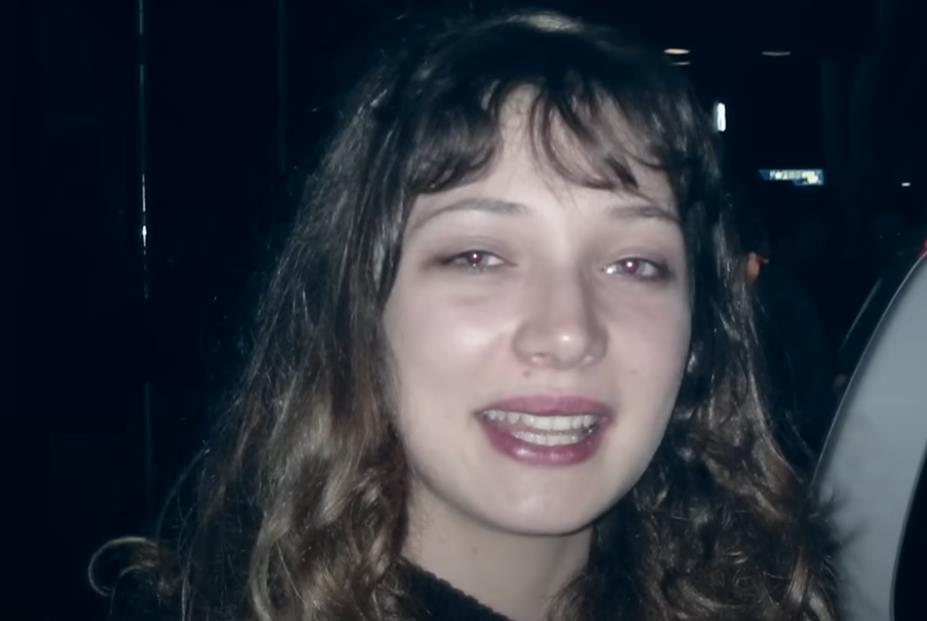 Merilin Beržeron stoji pored belih kola.jpg