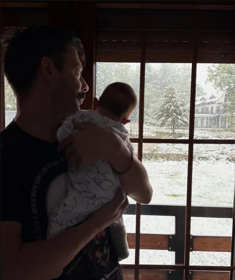 Milan Vasić drži sina u naručju dok gledaju kroz prozor.jpg