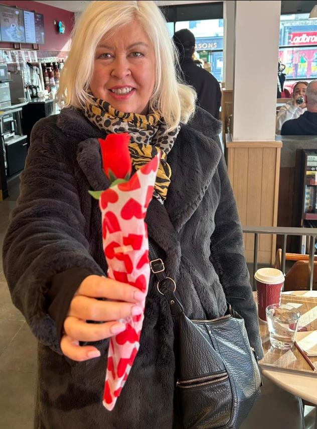 Džejn Doson u zimskoj jakni drži crvenu ružu .jpg