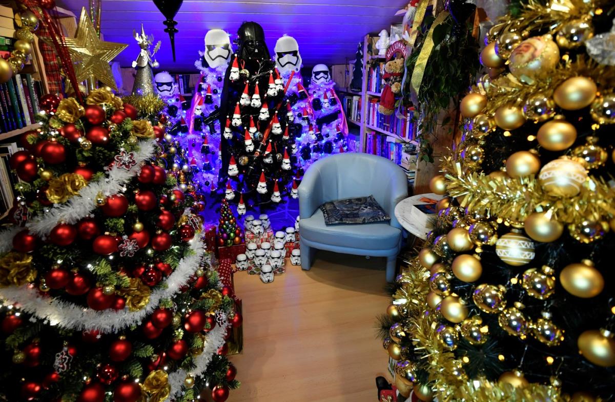 Unutrašnjost kuće sa desetinama okićenih božićnih jelki prepunih lampica