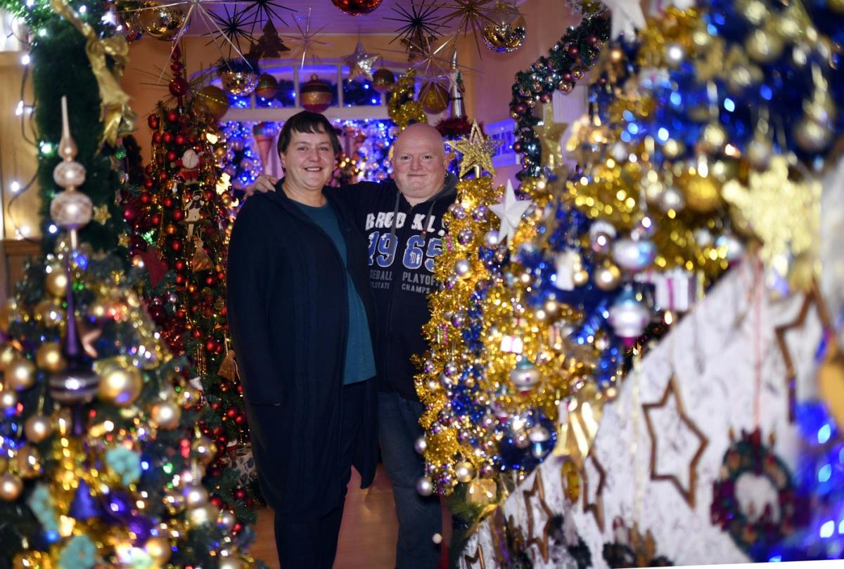 Unutrašnjost kuće sa desetinama okićenih božićnih jelki prepunih lampica