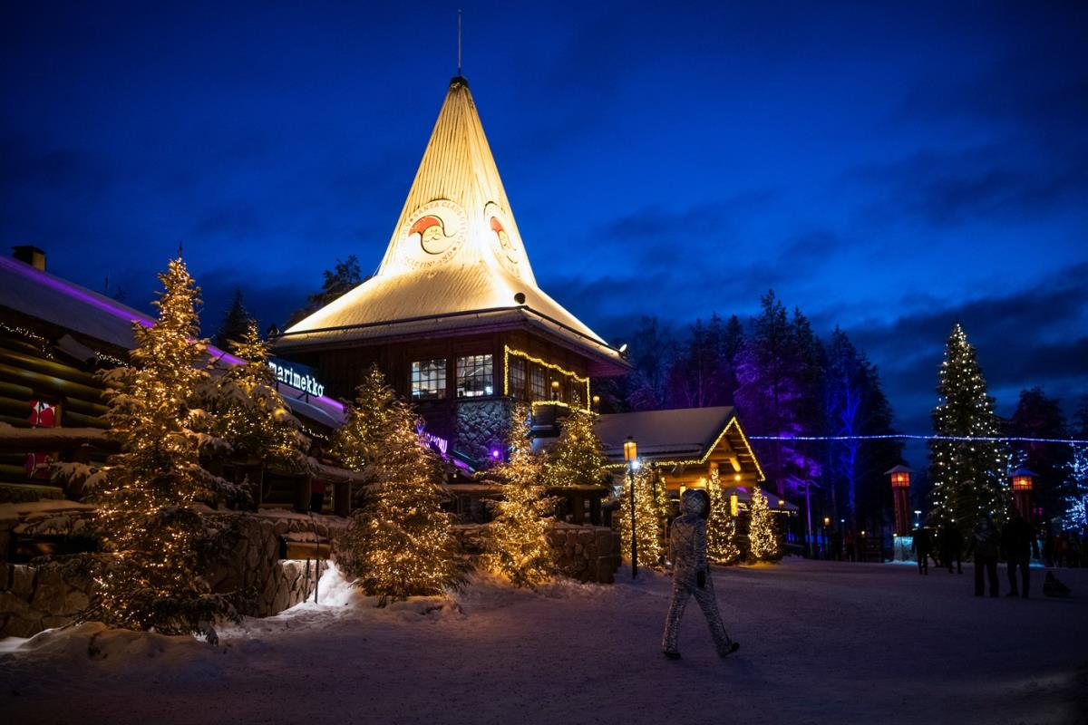 Božićno selo u Rovaniemiju sa drvenim kućicama, irvasima i svetlima na Arktičkom krugu, simbol prazničnog veselja i obnove grada