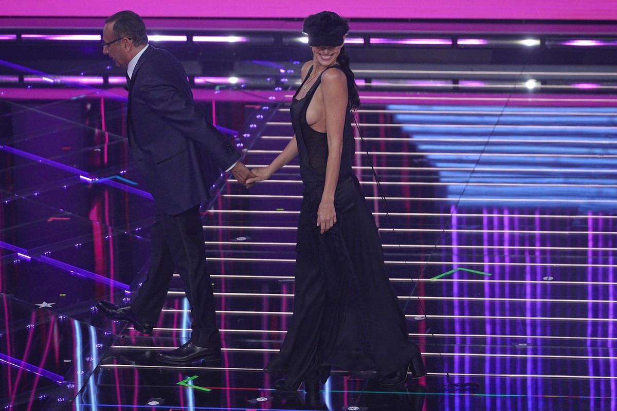 Irina Šajk blista dok nosi crni kombinezon na goloj koži, uparen sa šeširom sa perjem