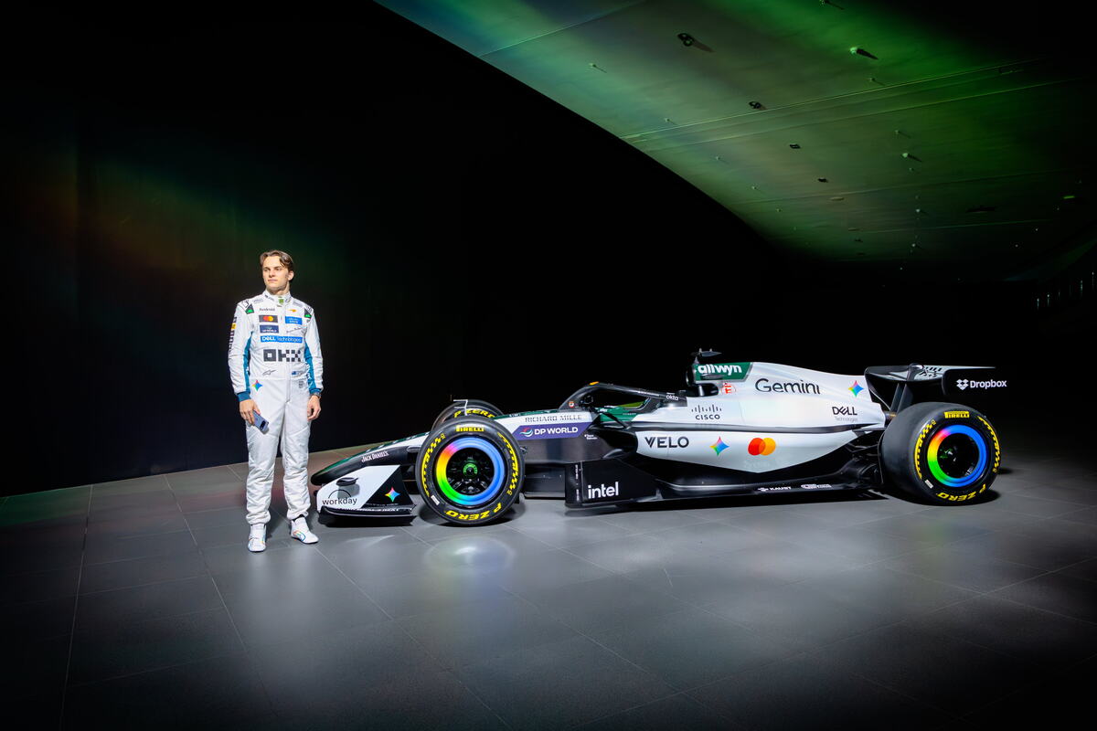 Oskar Pjastri pozira pored bolida Meklarena u belim bojama za trku u Silverstonu