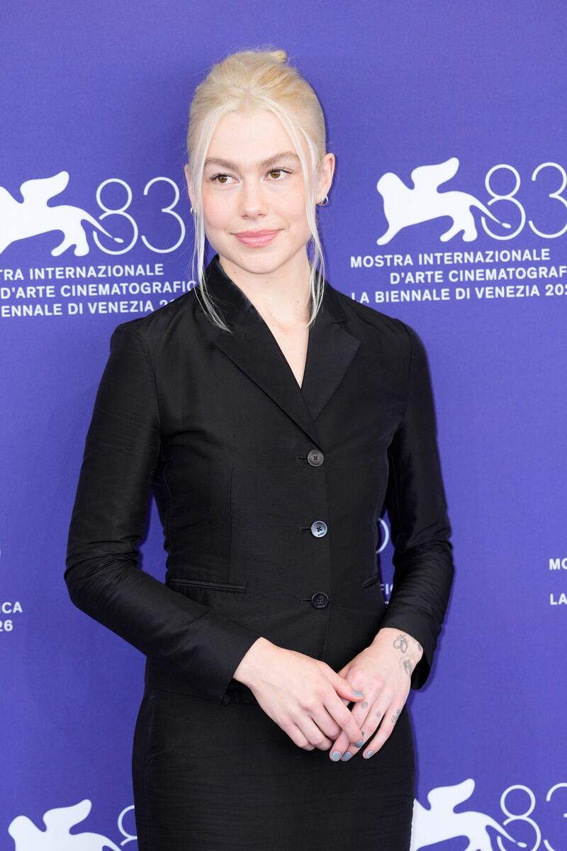 Fibi Bridžers na 83. Venecijanskom filmskom festivalu u crnom kompletu sa vidljivim prirodnim dlačicama na nogama