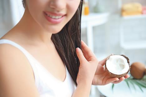 stockphotoyoungwomanapplyingcoconutoilontohairathome1065251234.jpg