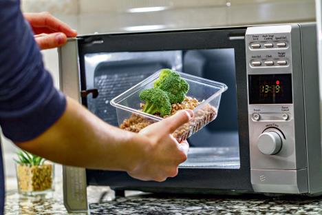 0802-stockphotousingthemicrowaveoventoheatfoodwomanshandputsplasticcontainerwithbroccoliand1266449479.jpg