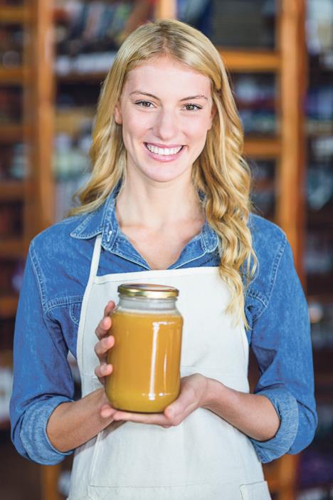 stockphotoportraitofsmilingfemalestaffholdingjarofhoneyinsupermarket491378923.jpg