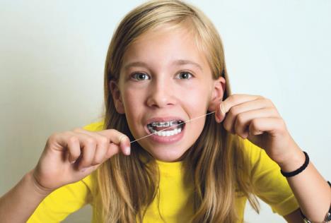 stockphotofunnygirlwithdentalbracesflossingherteethcloseupportraitofpreteengirlwithdental704397511.jpg