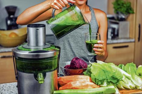 stockphotowomanjuicingmakinggreenjuicewithjuicemachineinhomekitchenhealthydetoxvegandietwith718961371.jpg