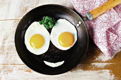 stockphotosmilinghappyfacefryingeggsbreakfastwithparsleyinironvintagepotonwoodentable250745545.jpg