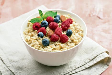 stockphotooatmealwithraspberriesalmondsandblueberriesandmintonpinkbackground1454770658.jpg