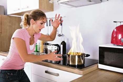 stockphotoshockedyoungwomanlookingatcookingpotwithfirenearmoderngasinkitchen792865270.jpg